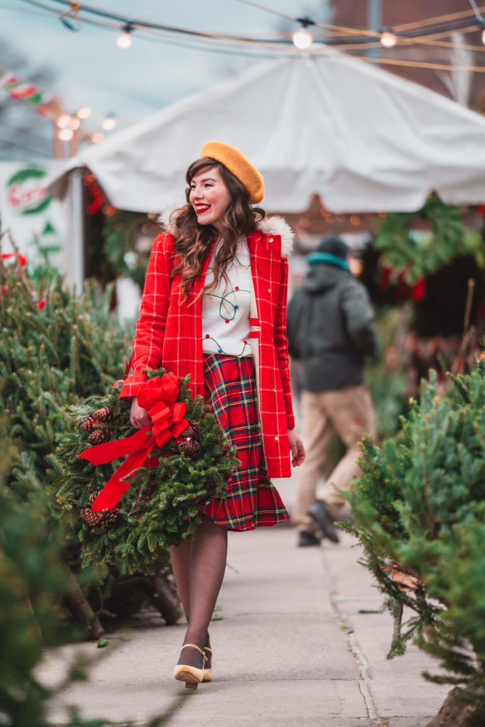 Blogger wearing a tartan skirt and red jacket.