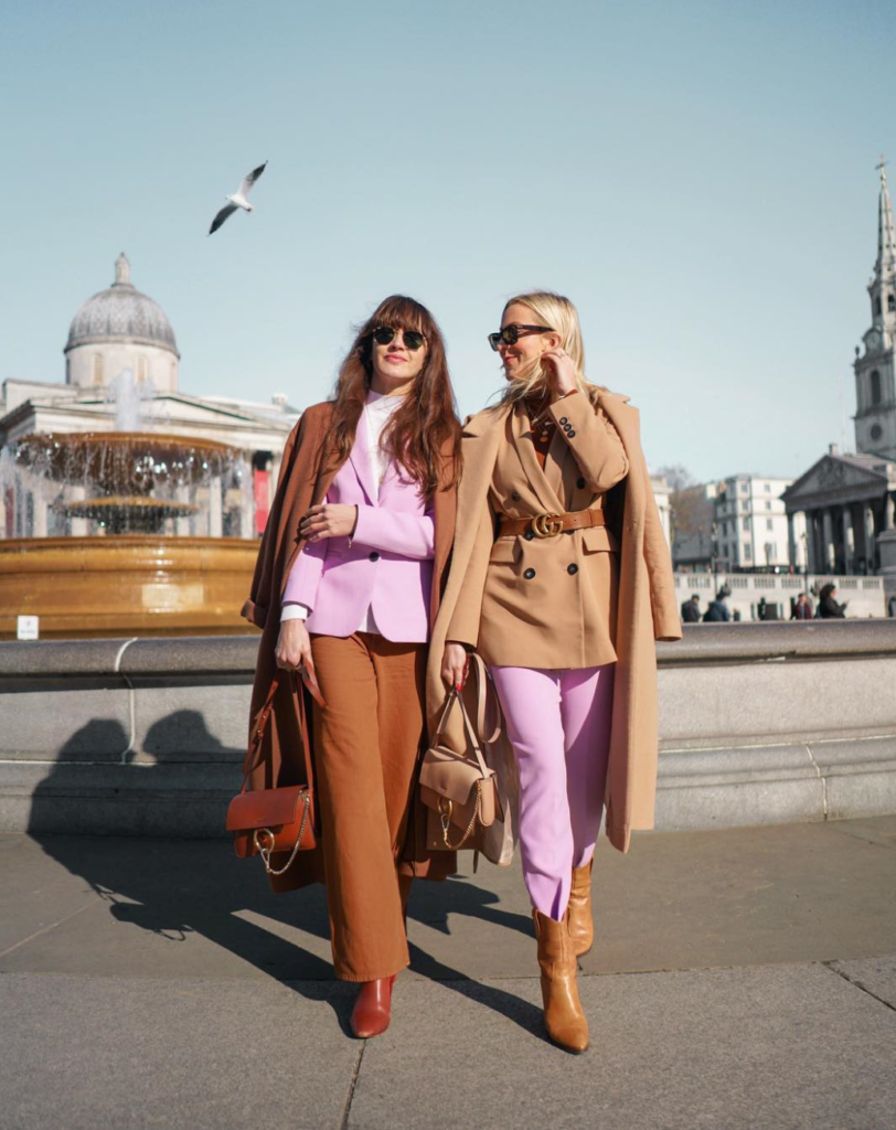 Two women wearing neutral colors with pastel pink.