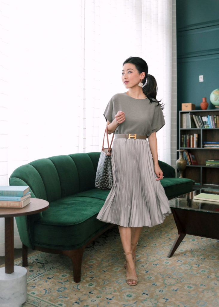 Blogger wearing a pleated skirt in a living room.