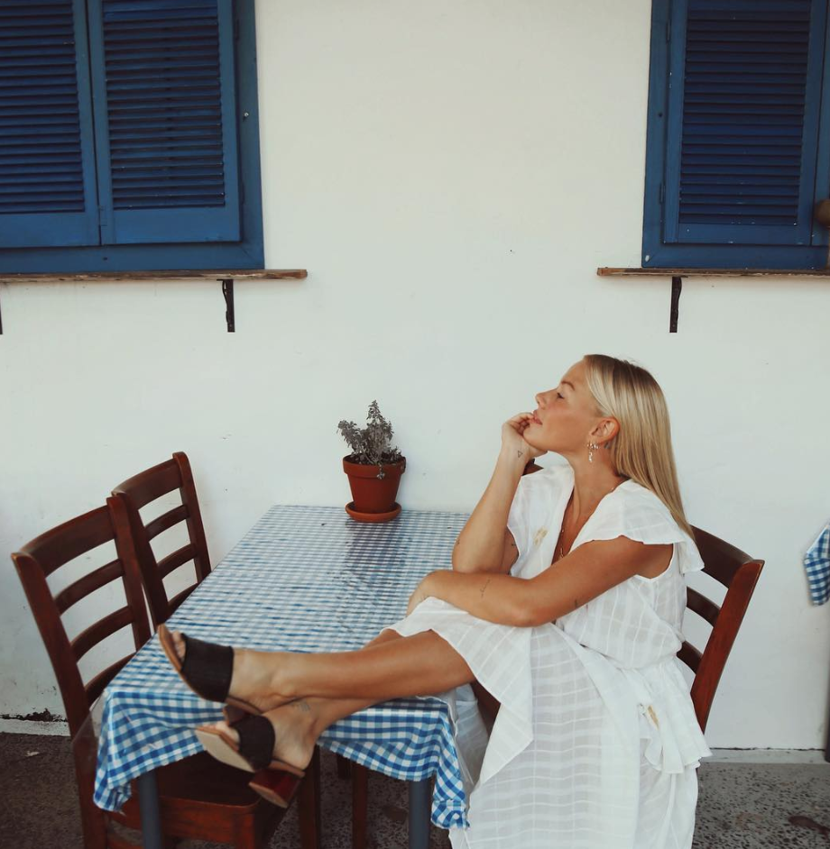 Blogger wearing a white summer dress at an outside eating table.