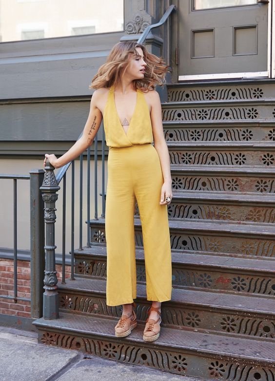 Woman wearing yellow jumpsuit on stairs.