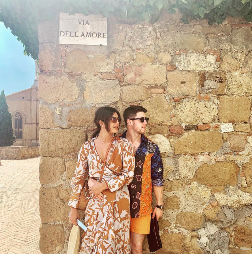 Couple wearing matching outfits against a wall on vacation.