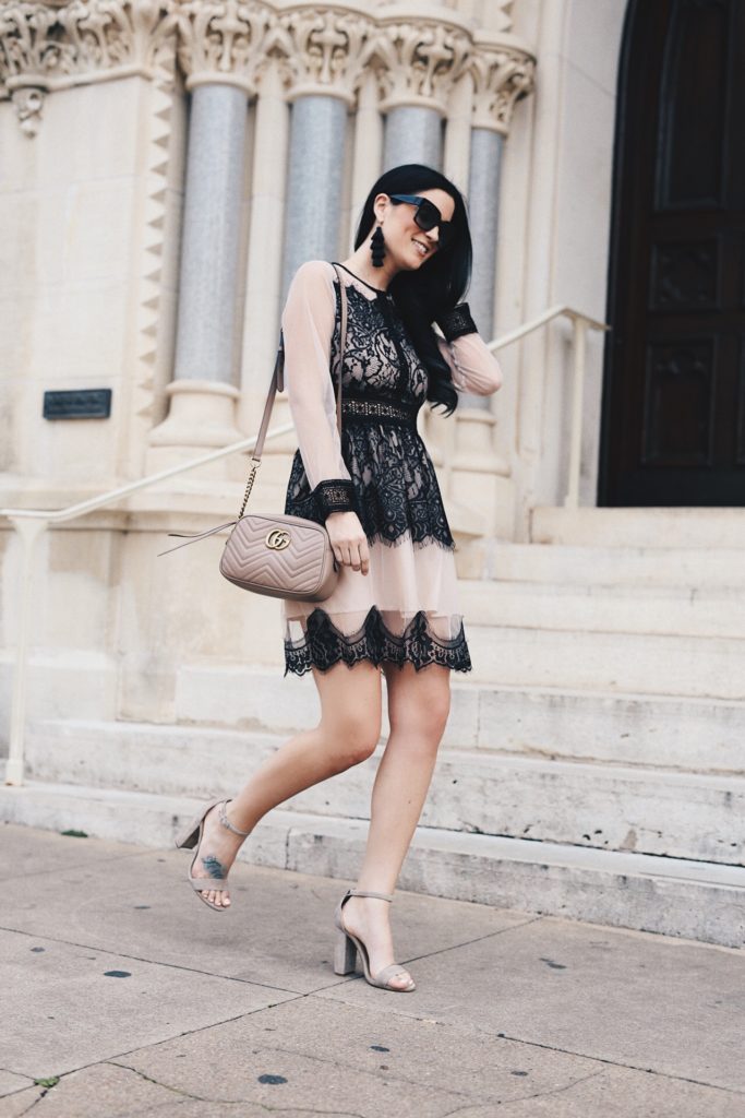 Woman wearing a nude dress with lace detailing outside of a building