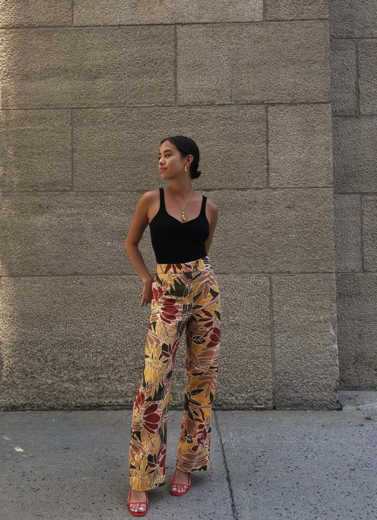 Woman wearing printed floral pants with plain black tank top.