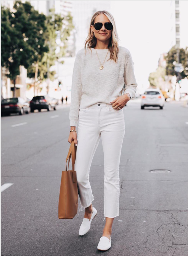 Woman on the street wearing an all white outfit with brown purse.