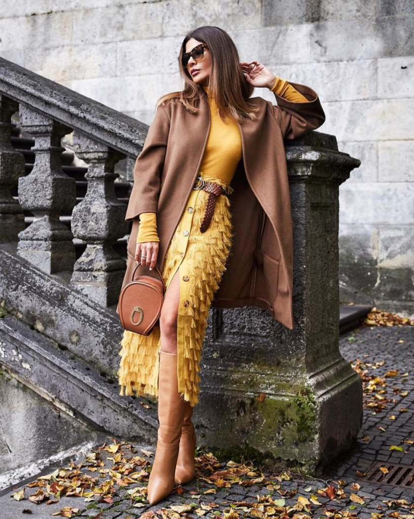 Woman combing yellow pieces with a brown jacket and accessories.
