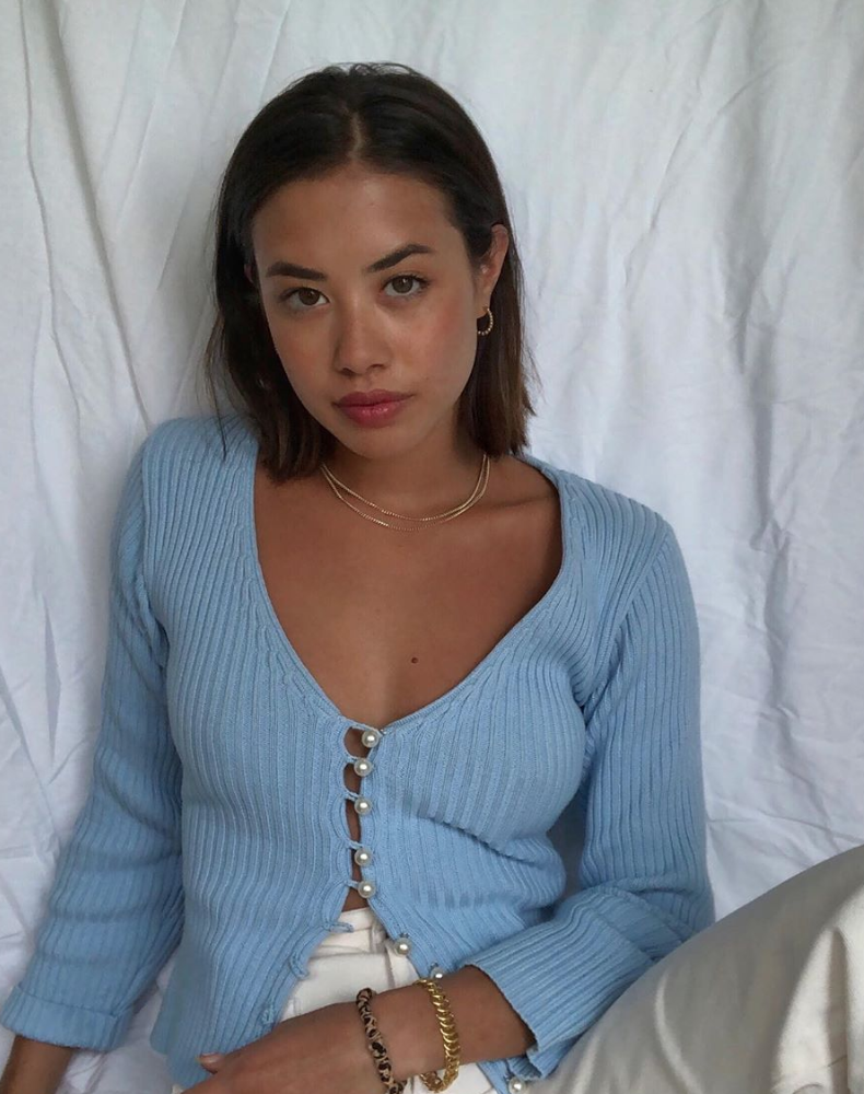 Woman wearing blue pastel sweater against white backdrop.