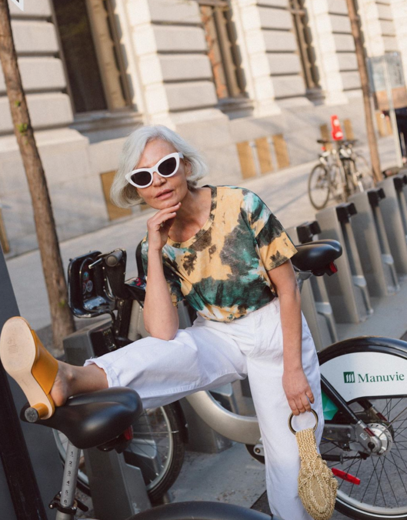 Blogger sitting on a rental bicycle in patterned top.