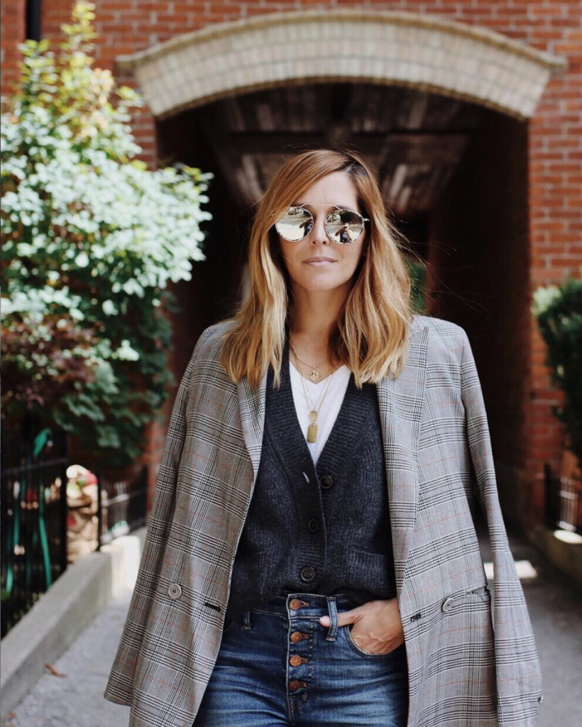 Woman in a walkway layering a cardigan and blazer.