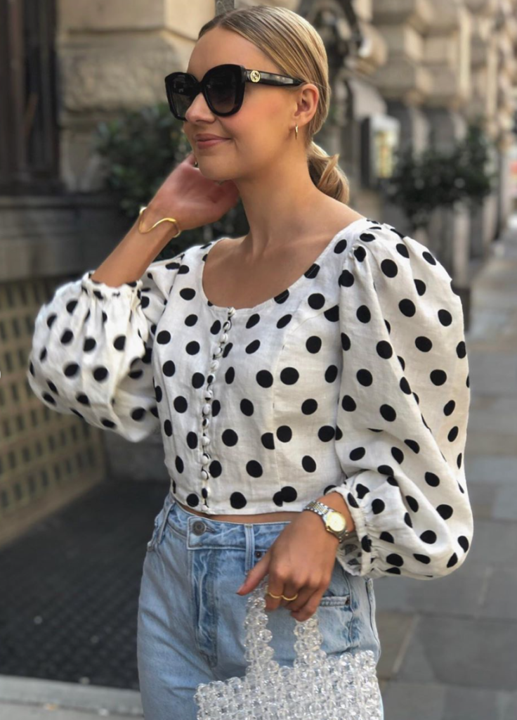 Woman wearing polka dot shirt with puffy sleeves.