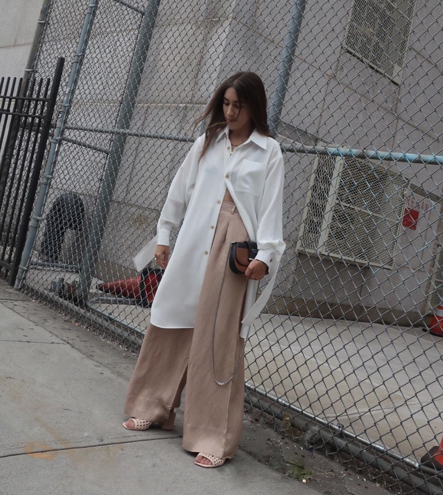 Woman wearing oversized pieces in front of a fence.