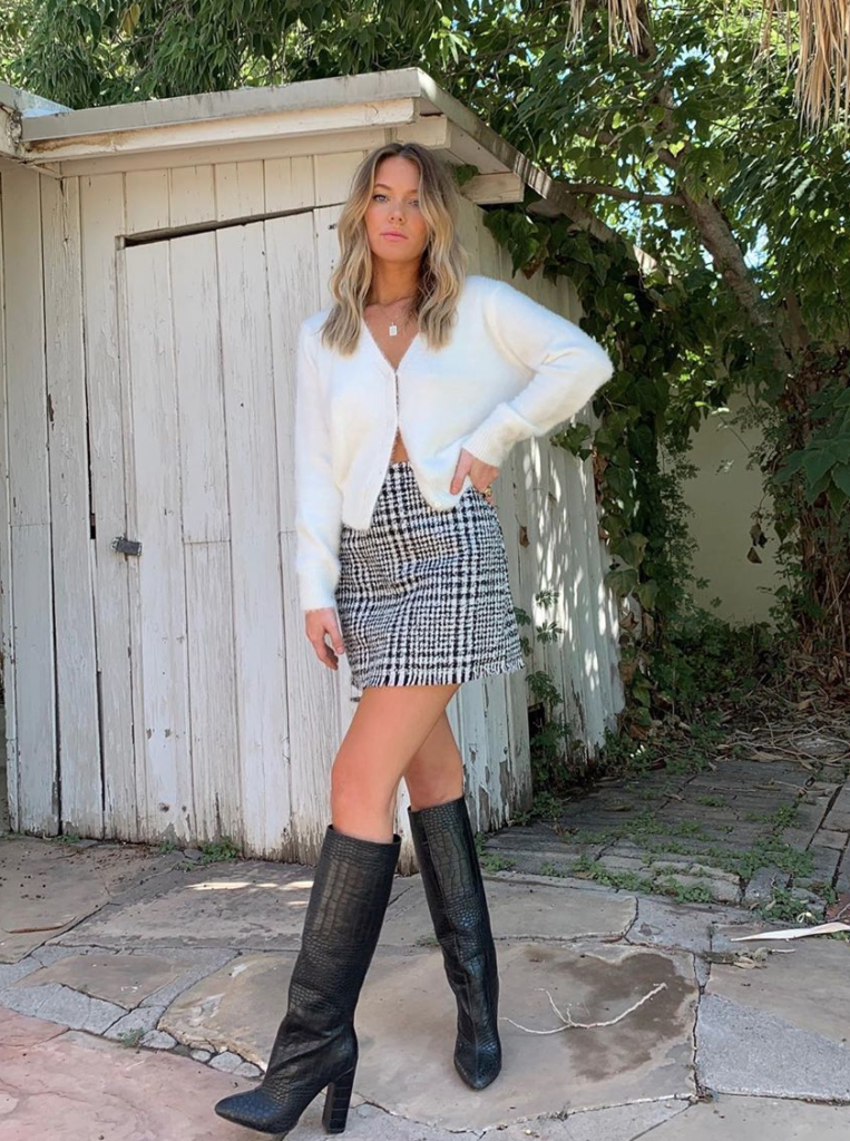 Influencer wearing white cardigan with patterned skirt.