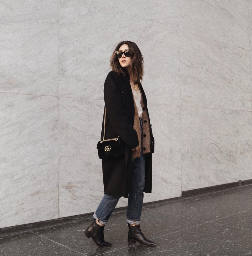 Blogger layering a cardigan underneath an overcoat and denim.