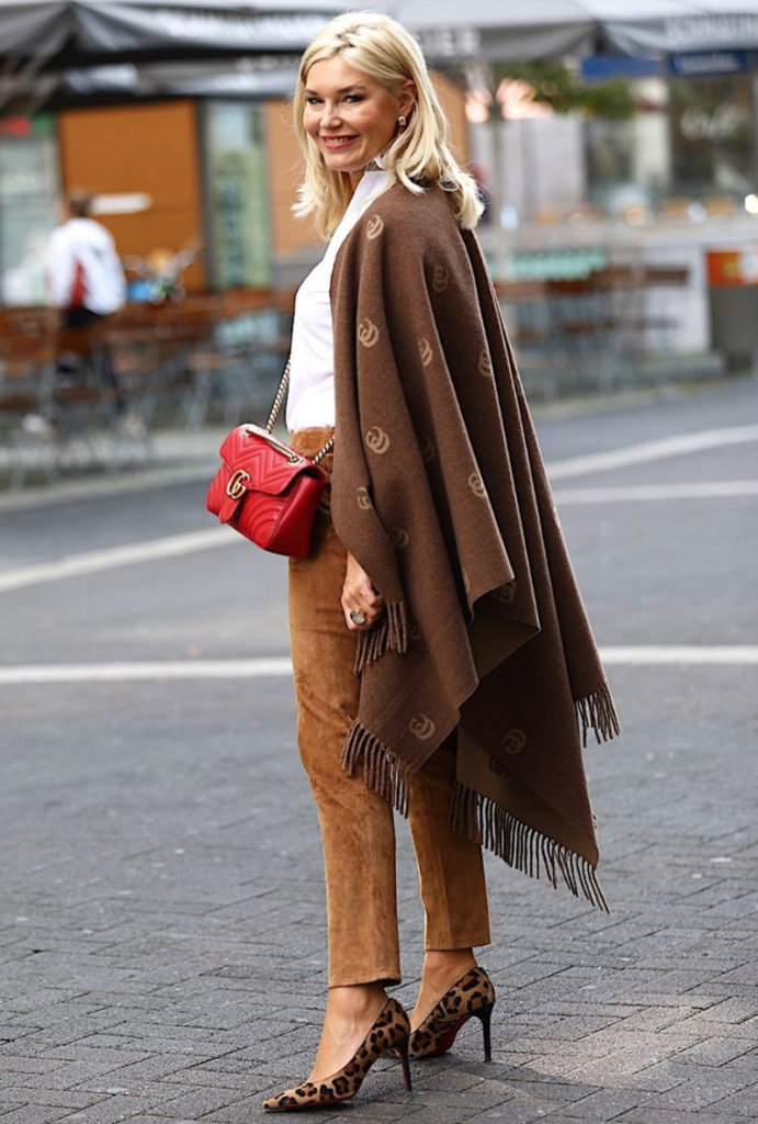 Woman layering a a white shirt with a brown cape.