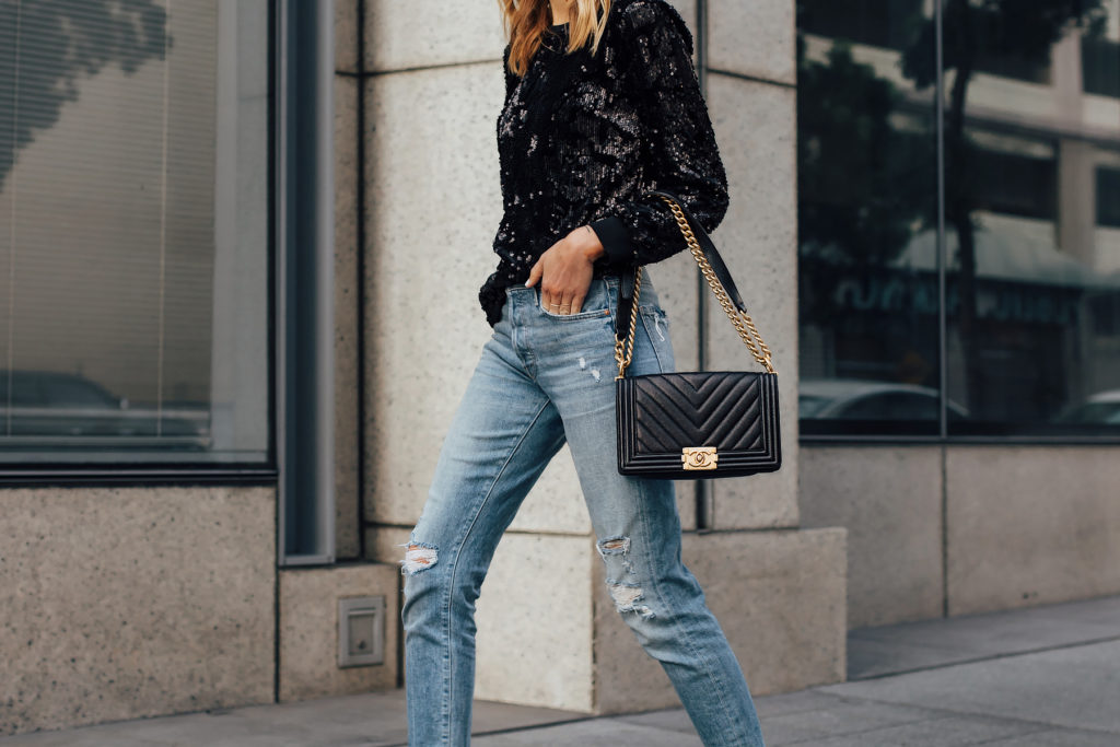 Woman wearing black sequins shirt with denim for holiday season inspiration.