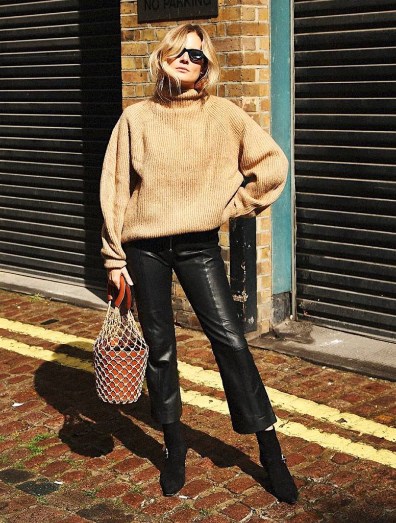 Woman pairing crewneck with leather pants for holiday season style.