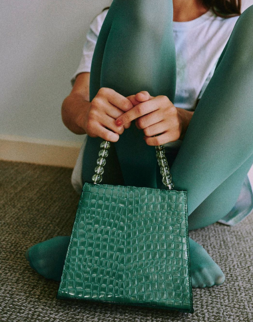 Woman highlighting faux croc-designed purse.