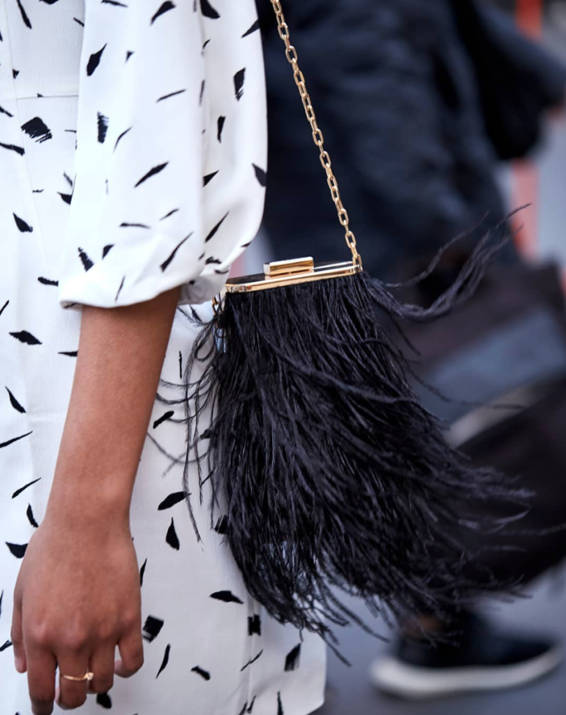 Woman wearing accessories and crossbody designed like feathers.