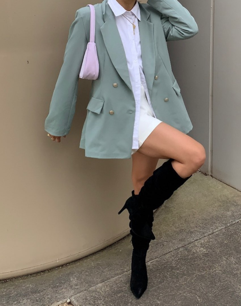 Woman wearing blouse and blazer with knee high boots as our must-haves.