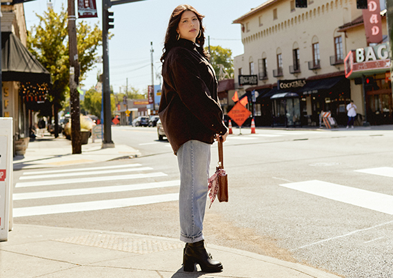 Model in brown shirt standing on the sidewalk.