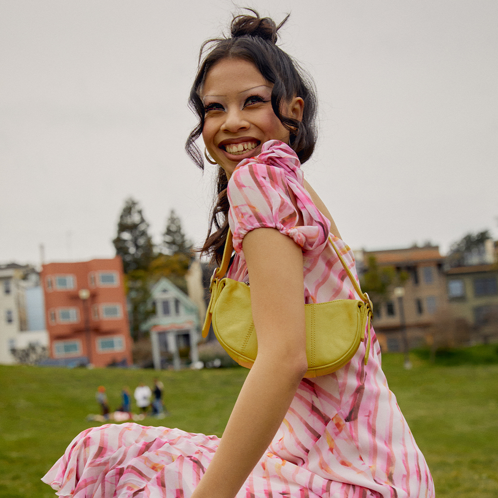 Model wearing a pink dress holding a yellow purse