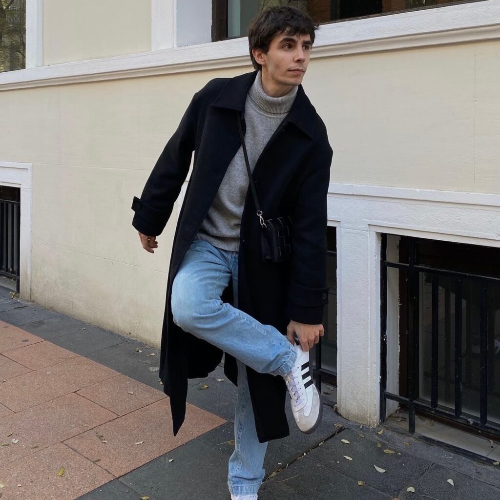 photo of person wearing an oversized coat, jeans, and sneakers