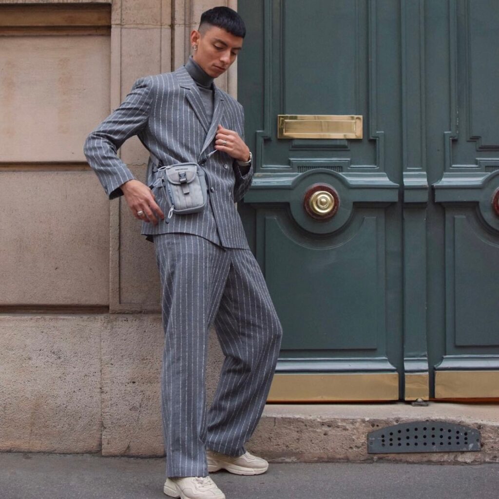man wearing a pinstripe set with gray crossbody and sneakers