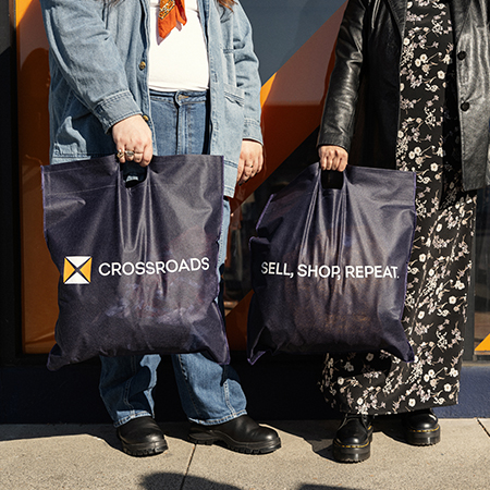 two people holding Crossroads shopping bags after getting cash for clothes