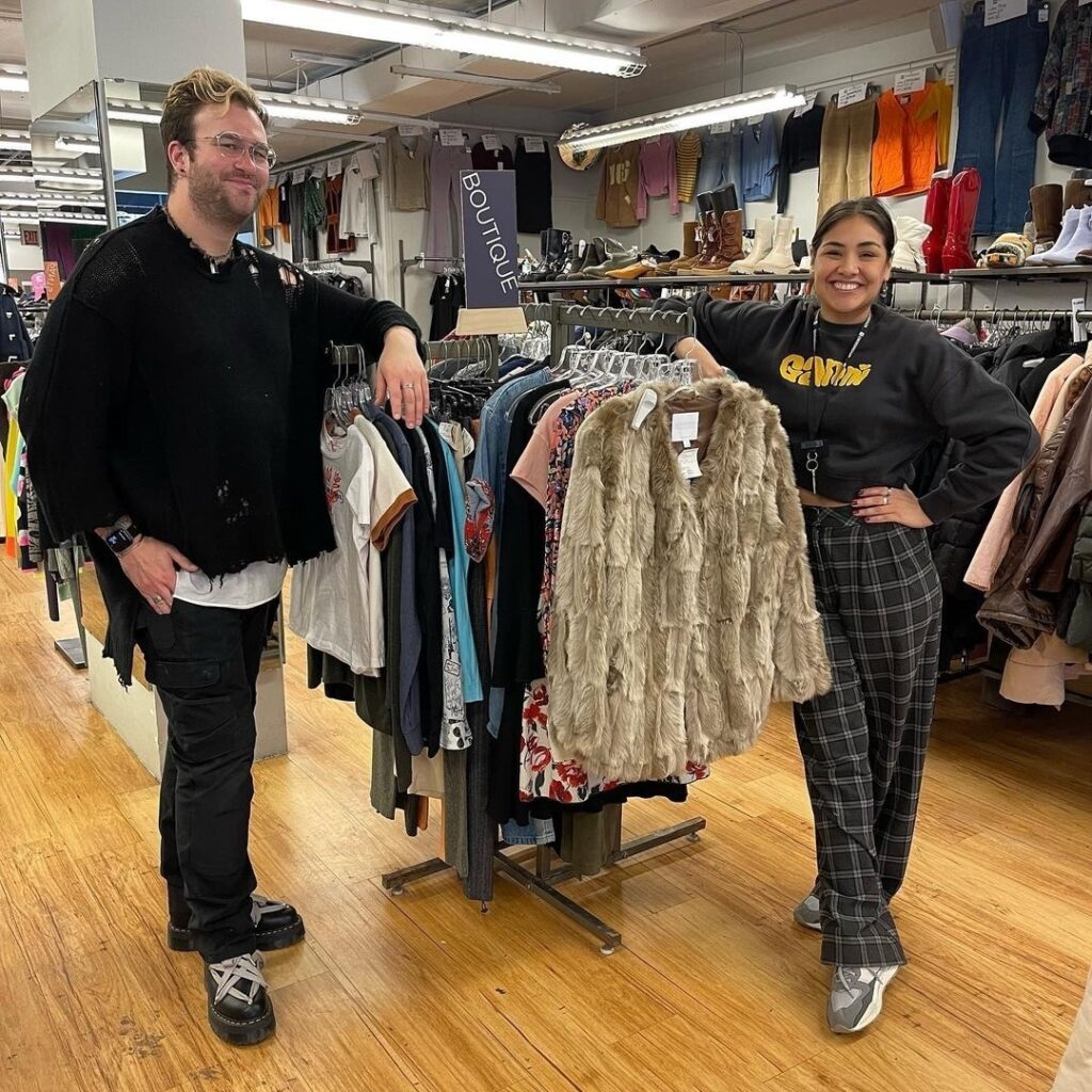 two employees standing at a clothing rack, working retail jobs in fashion