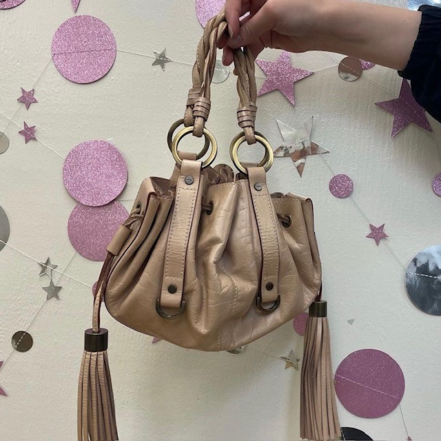 A thrift fashion handbag in beige with tassels