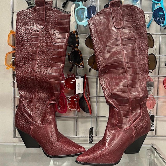 a pair of tall red mock reptile boots in a thrift fashion store