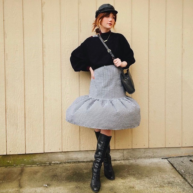 woman in black sweater and gray plaid skirt with flounce hem