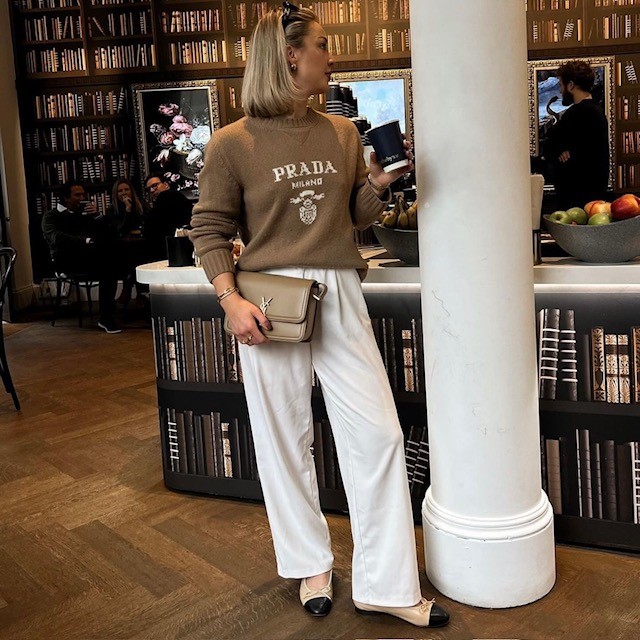woman with beige sweater, wheat colored trousers, and Chanel shoes