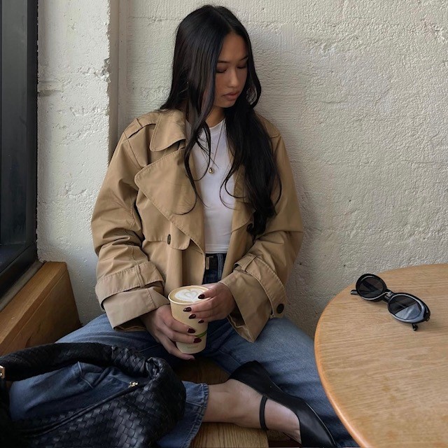 woman with trench coat, white tee, jeans, and black ballet flats