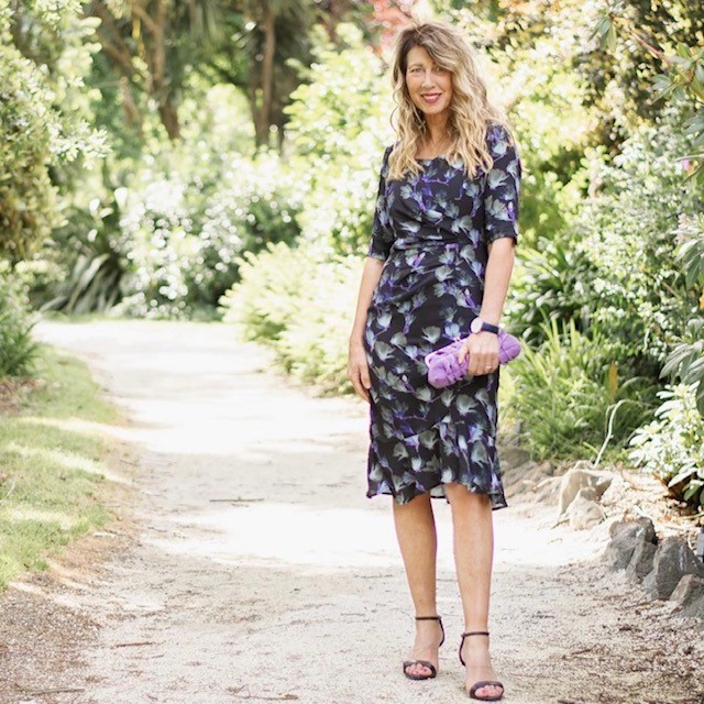 Woman in black floral mid-length dress and black strappy sandals