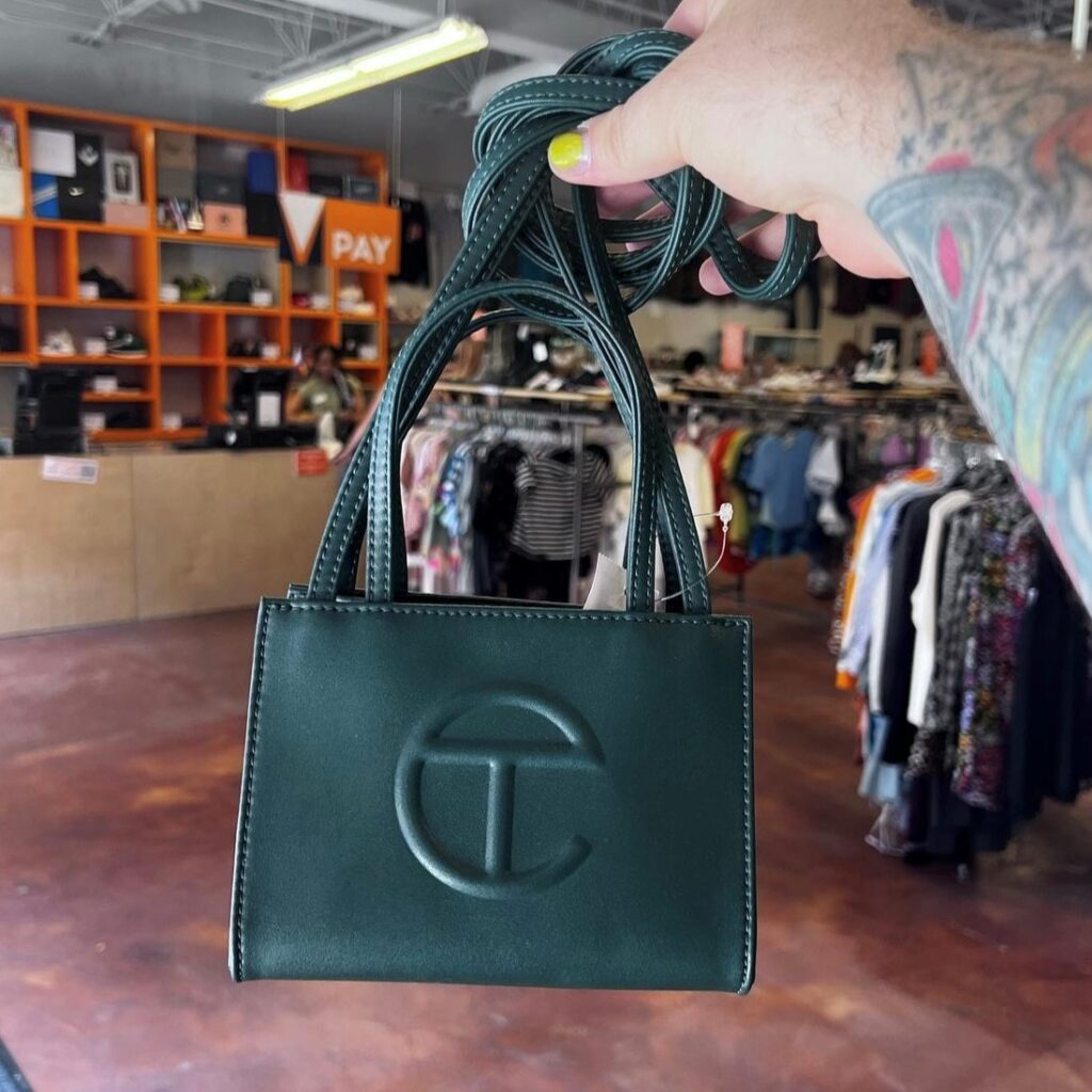 person holding out a small forest green Telfar bag
