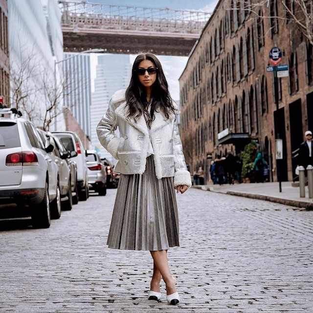 woman on city street wearing a silver pleated skirt and jacket