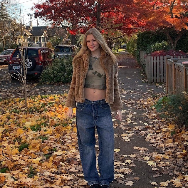 woman in crop top, jeans, and brown jacket