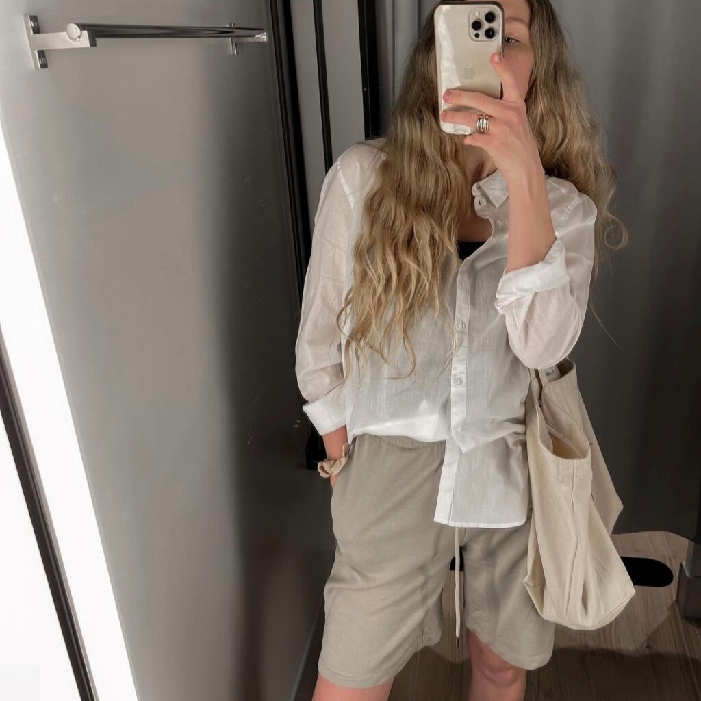 person taking a selfie in a white linen shirt and beige loose fitting shorts