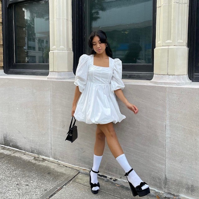 Woman in white babydoll dress with white socks and black heels