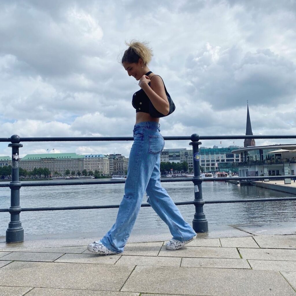 woman walking along canal in denim pants and black tank top