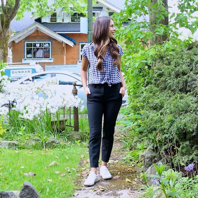 woman wearing a checked shirt, black pants, and slim sneakers