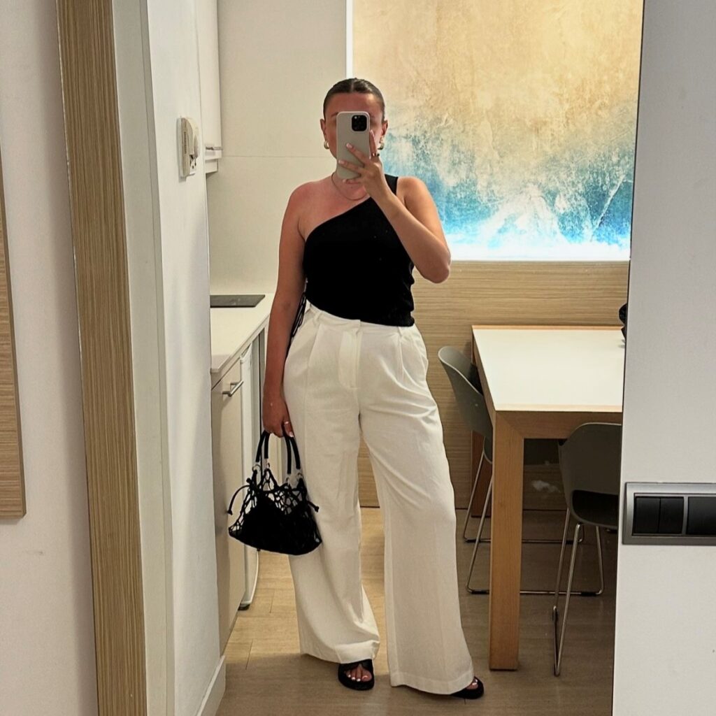 woman in white linen pants and black one-shoulder top