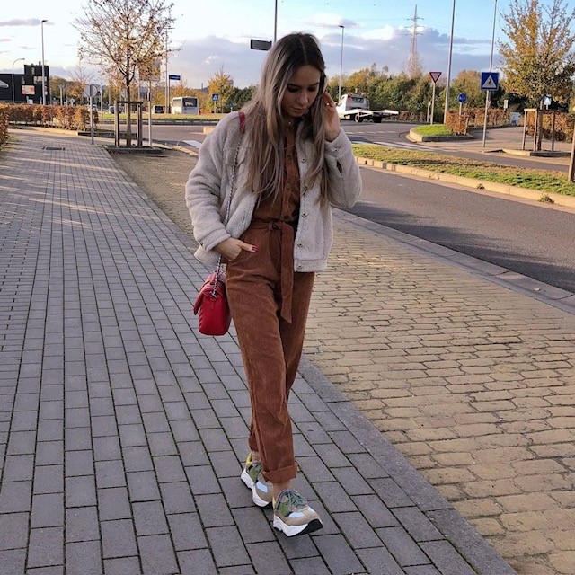 woman wearing a brown jumpsuit with trainers and a beige cardigan