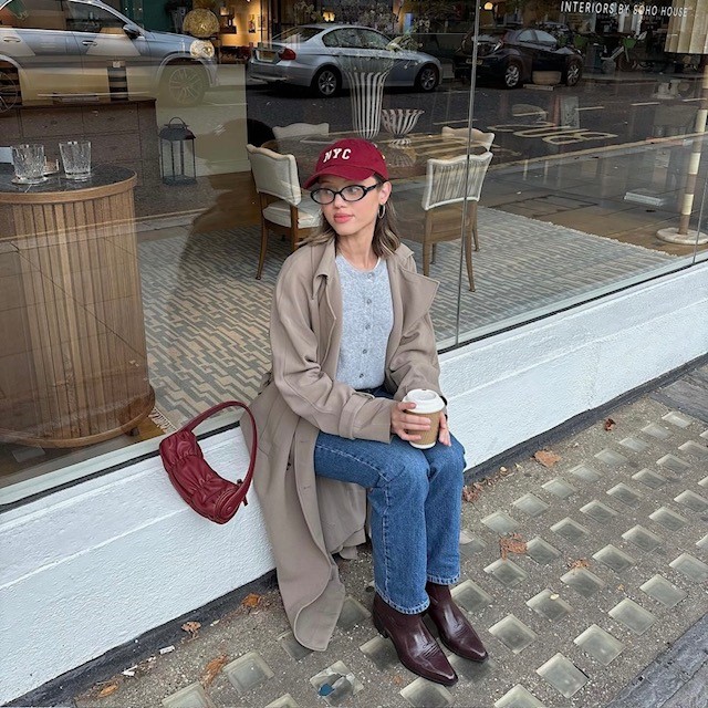 woman wearing brown cowboy boots, jeans, gray cardigan, and trench coat