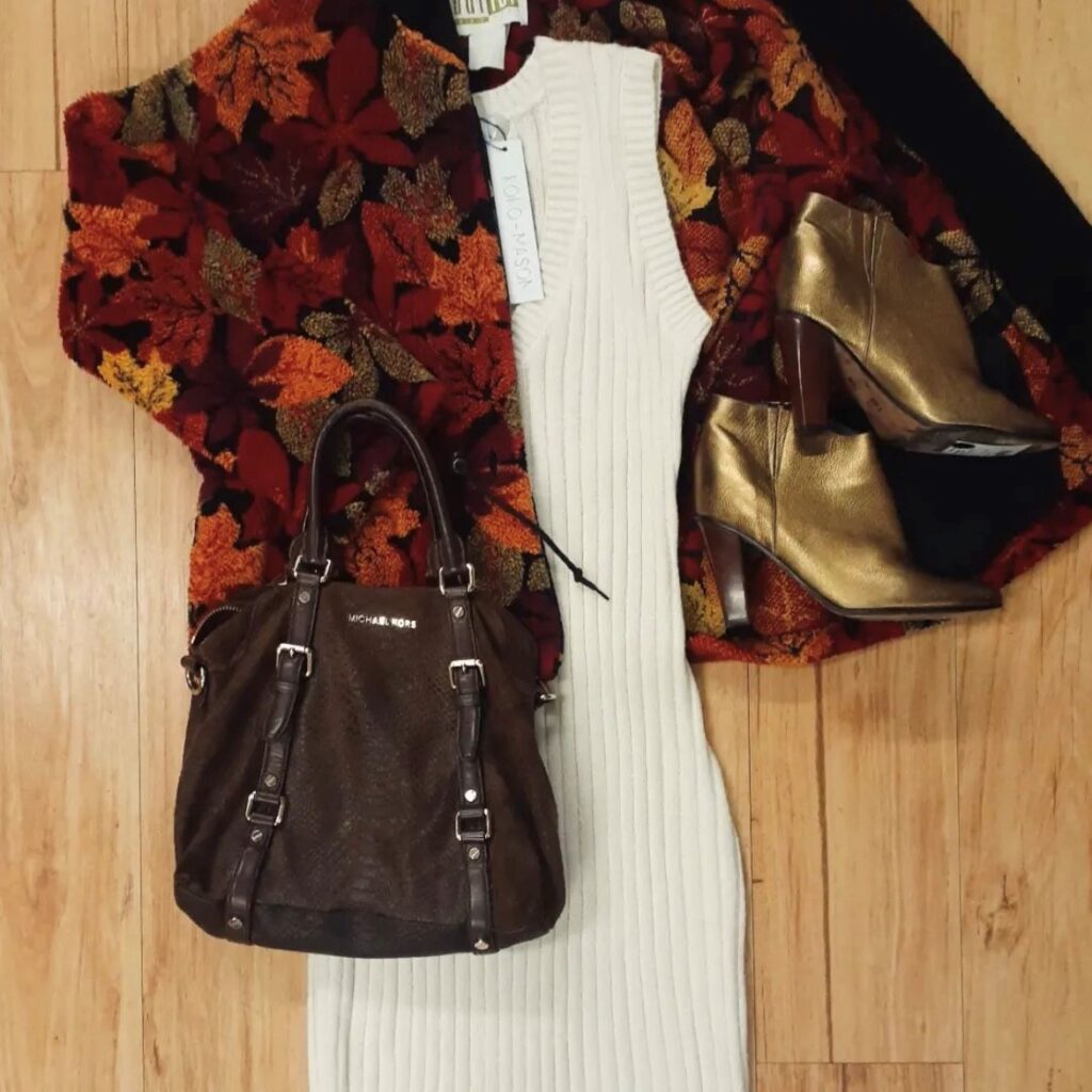 clothing flatlay with Michael Kors oversized handbag in brown, a leaf-print sweater, and cream colored dress