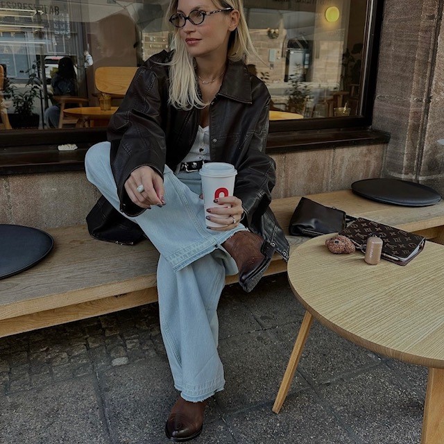 woman wearing a brown pair with baggy light denim jeans, tee, and leather jacket