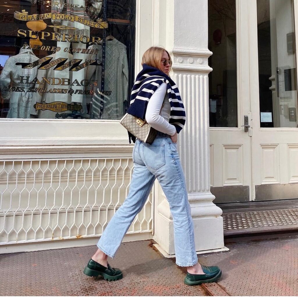 woman wearing green platform loafers with jeans and a long sleeve shirt