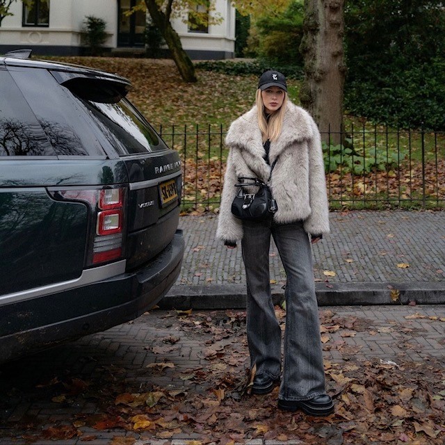 woman in faux fur jacket with jeans and a baseball cap