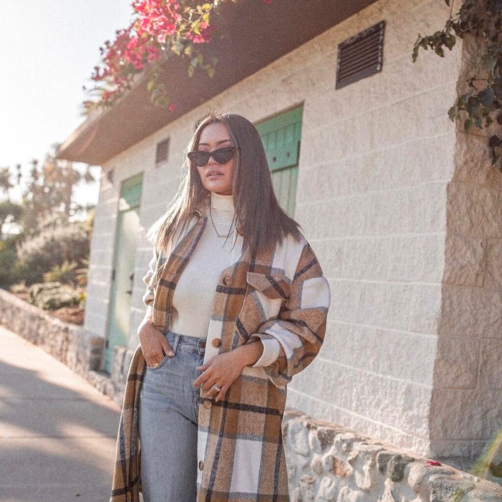 woman wearing a turtleneck and jeans with long plaid jacket